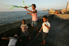 Children playing on the shore. The coastline is the walking zone for tourists and locals, a place for morning runs, a meeting place of  street musicians, children and freelance artists. Flyinf a kite is a popular children's amusement. Habana, Cuba, Thursday, Feb. 22, 2007.