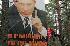 Activist of the pro-Kremlin youth movement 'Nashi' hangs the flag of his delegation next to a poster showing the Russian President Putin in the Nashi summer camp on Lake Seliger, some 300 kilometres (~180 miles) northwest of Moscow, Tuesday, July 17, 2007. Pro-Kremlin Nashi (Ours) youth movement has assembled about 10 thousand young people from all over Russia to a summer camp where they are going to do sports and attend political and socially oriented lectures and training sessions for two weeks.